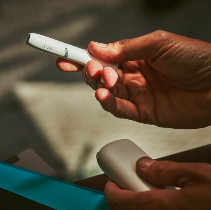 IQOS white, l'holder nella mano destra, il charger nella sinistra