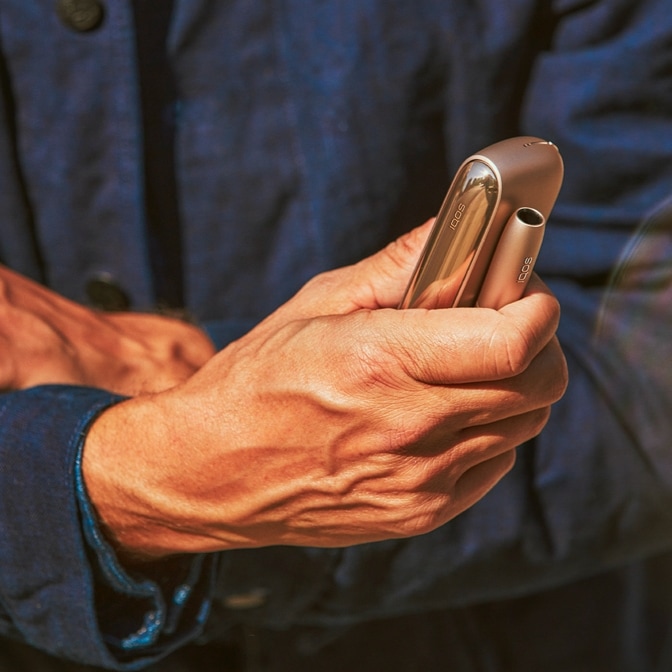 Holder e charger IQOS brilliant gold in una mano maschile
