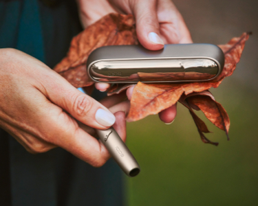 An IQOS device in a person's hand.