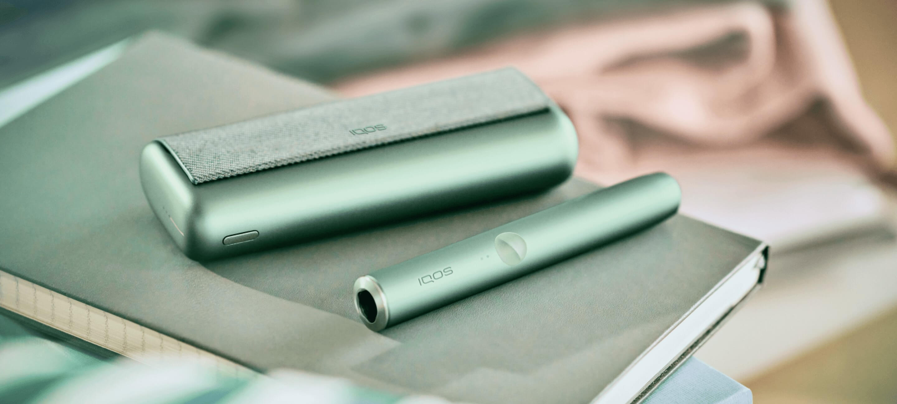 A person holding an Obsidian Black IQOS ILUMA PRIME Holder and Pocket Charger.