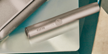 Dispositivo IQOS ILUMA Azure Blue in carica su un tavolo.