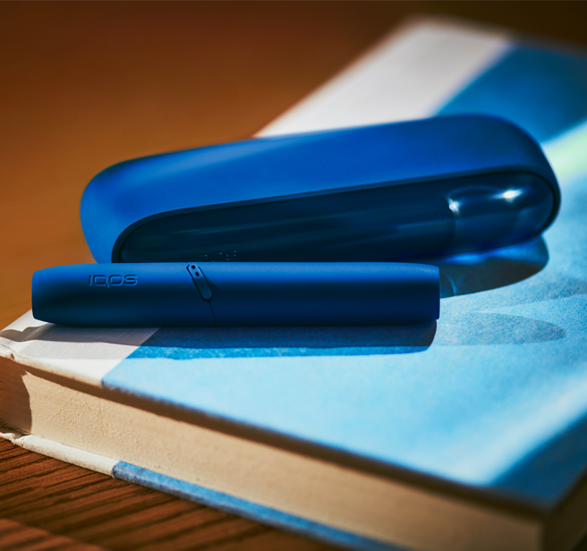 A Stellar Blue IQOS on a notebook.