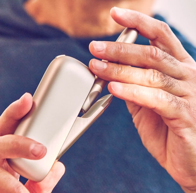 Mani che tengono un dispositivo IQOS