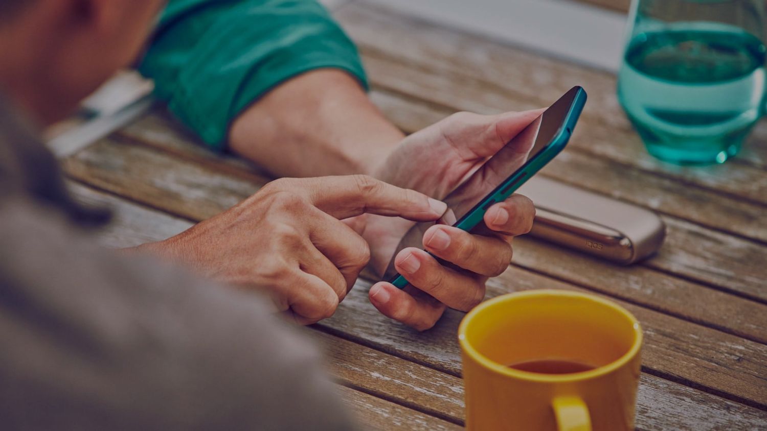 Uomo che usa il telefono con IQOS sul tavolo