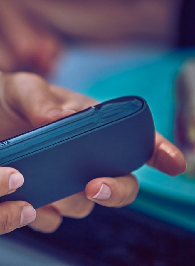 Woman holding her grey IQOS - IQOS charging slowly