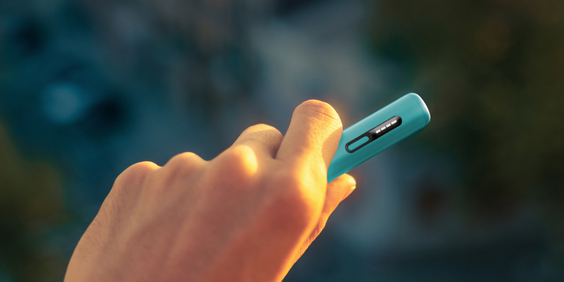 Garnet Red IQOS ILUMA i device and its charger on a blue fabric