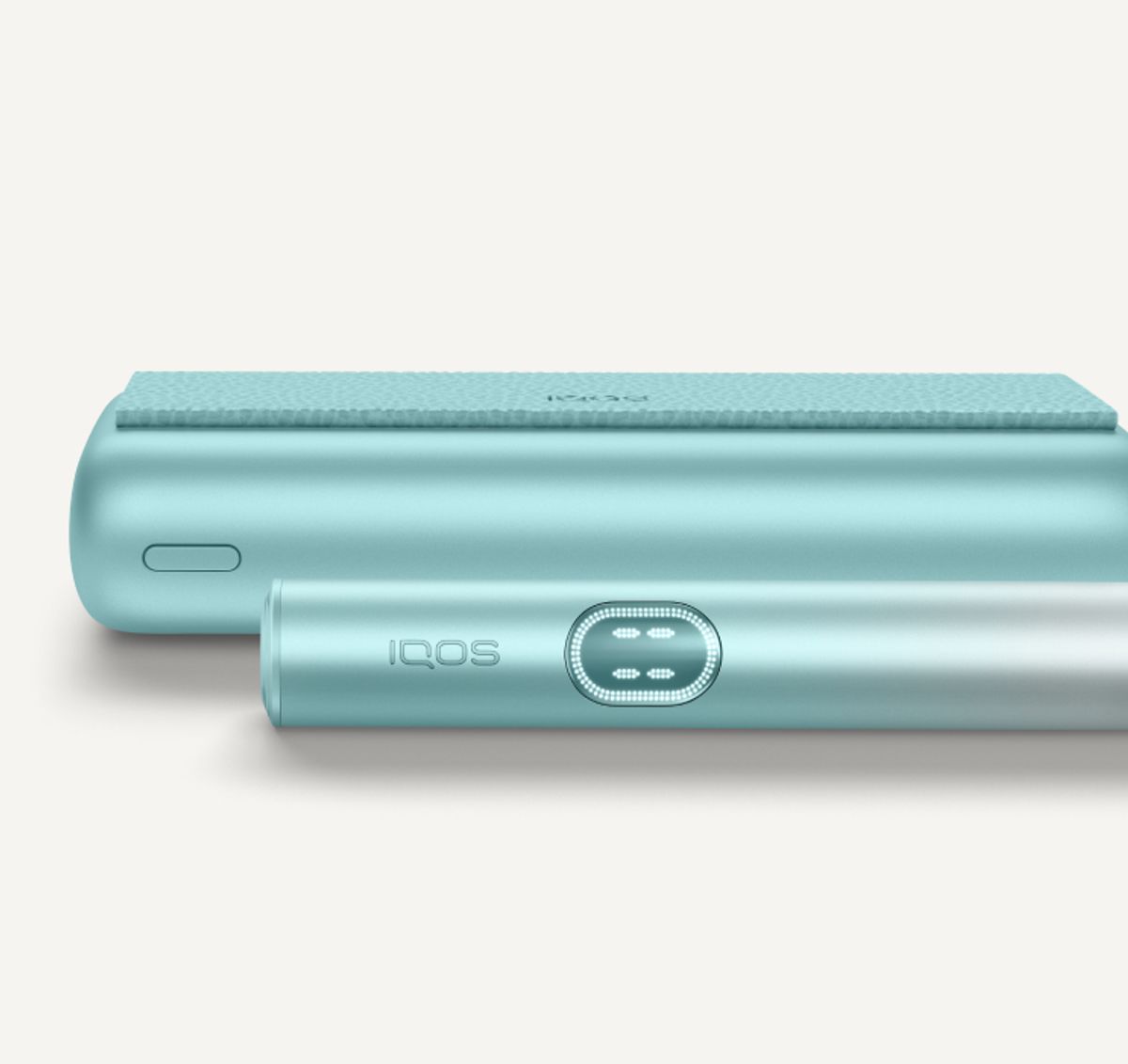 Dispositivo IQOS ILUMA i PRIME di colore turchese Breeze Blue. Composto di un caricatore tascabile e un holder poggiati su una texture di pelle