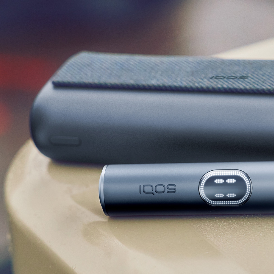 IQOS ILUMA i PRIME nel colore nero con cariatore e holder su un tavolo marrone