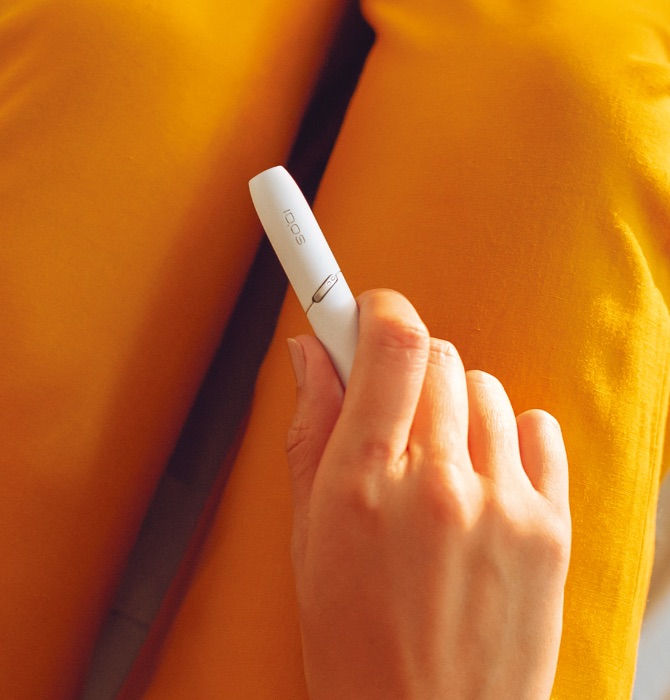 Brilliant gold IQOS 3 DUO with HEETS stick on top of charger
