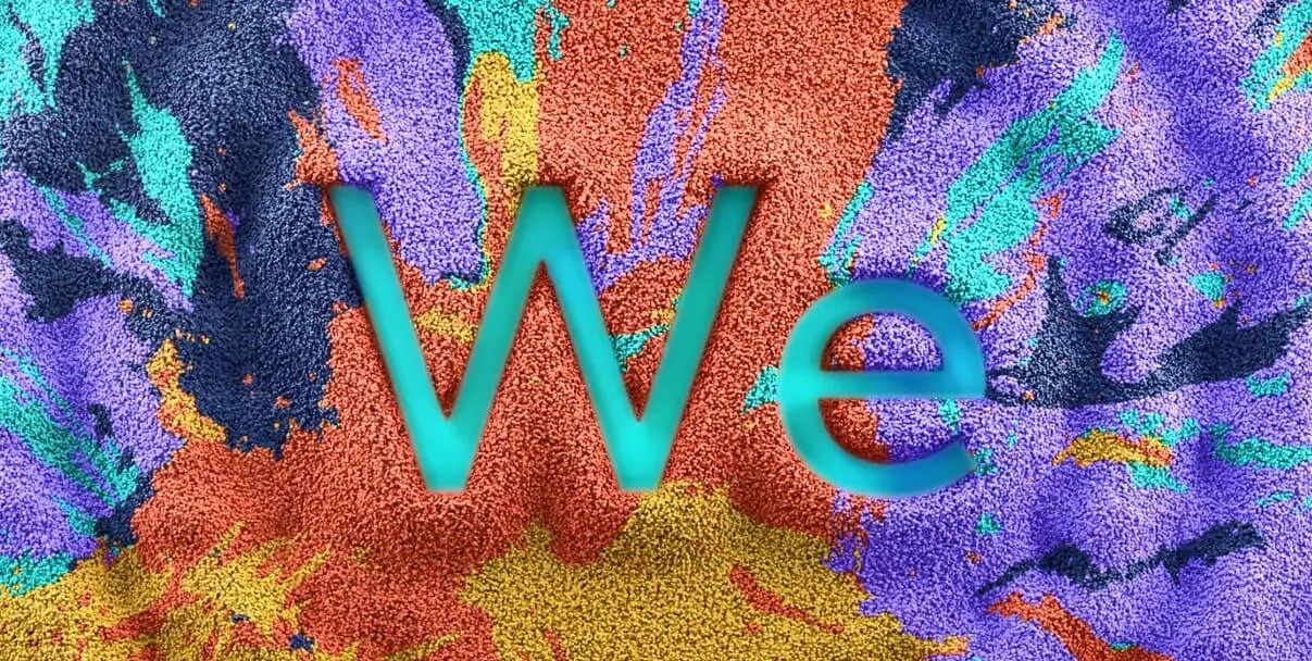 A blend of blue, purple, orange yellow and turquoise colour powders creating a circle with the word 'We' in the middle .
